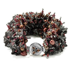 May include: A beaded bracelet with a silver clasp. The bracelet is made with black, brown, and silver beads. The beads are arranged in a cluster pattern.