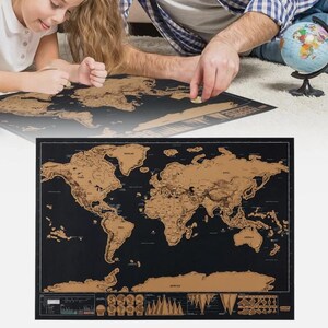 May include: A rectangular scratch-off world map featuring a black background with copper-coloured landmasses. The map displays detailed continental outlines, country borders, and various geographical charts and icons along the bottom edge.