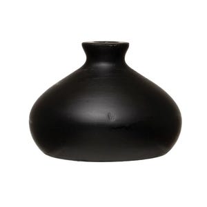 May include: A matte black vase with a rounded body and a narrow neck. The vase has a smooth, unadorned surface, and the dark color gives it a modern, minimalist aesthetic. The vase is suitable for home decor.