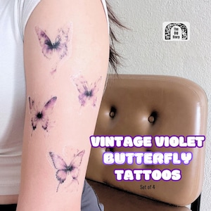 May include: Four vintage violet butterfly temporary tattoos on a person's arm. The tattoos are a light purple color and have a faded, vintage look. The text "Vintage Violet Butterfly Tattoos" and "Set of 4" is visible below the tattoos.