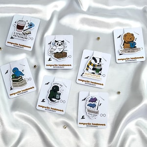 May include: A selection of magnetic bookmarks with cartoon illustrations and text. Designs include an owl, a badger, a lion, a bluebird, and other characters with coffee-themed phrases like "Espresso Patronum!" and "Sippin' and Schemin'."