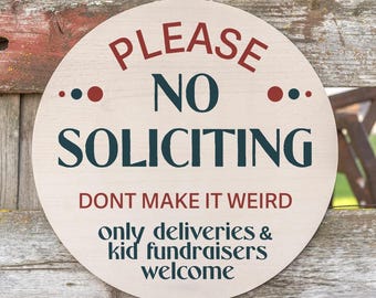 May include: Round wooden sign with the text "PLEASE NO SOLICITING" in red and navy blue. The sign also includes the phrases "DONT MAKE IT WEIRD" and "only deliveries & kid fundraisers welcome". The sign is hanging on a wooden fence.
