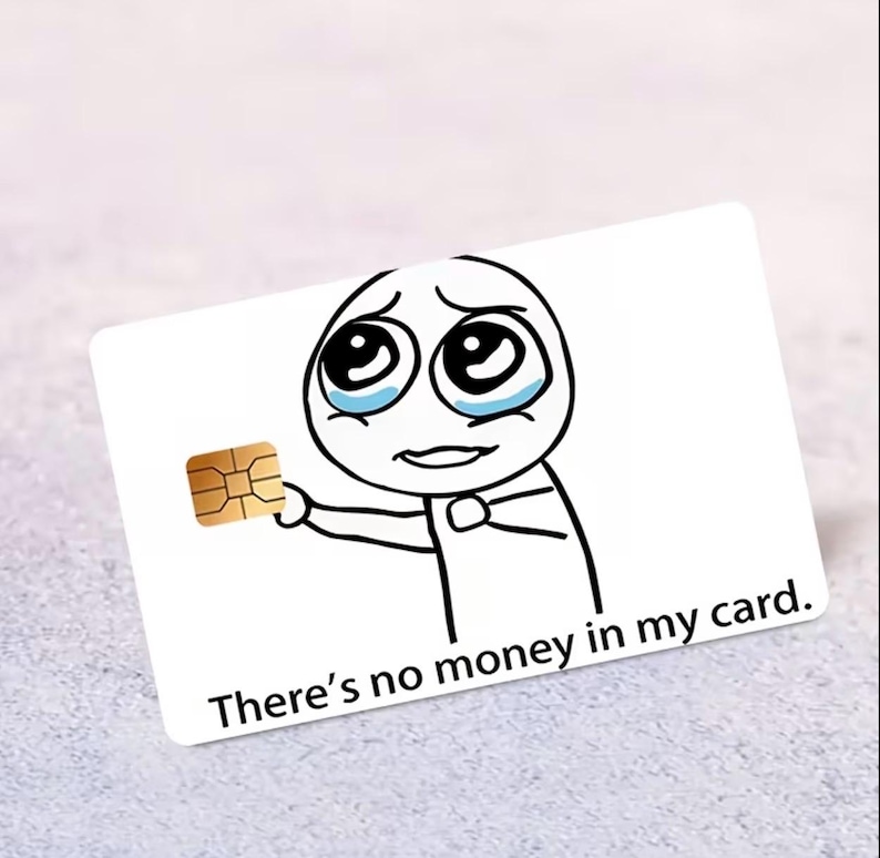 K&ouml;nnte beinhalten: Eine wei&szlig;e rechteckige Kreditkarte mit einer schwarzen Strichzeichnung einer traurigen, weinenden Figur, die einen goldenen EMV-Chip h&auml;lt. Der auf die Karte gedruckte Text lautet: There's no money in my card. Das Design ist mittig platziert.