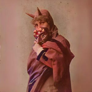 May include: A person wearing a red hooded costume with horns, holding a mask. The mask is dark with a detailed face. The costume has a red cloak and a fur-trimmed hood. The image has a vintage, sepia-toned aesthetic.