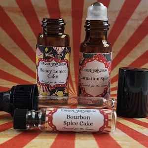 May include: Three glass bottles with rollerball tops and labels that read "CIRQUE SENSORIUM" and feature different scents: "Honey Lemon Cake", "Carnation Spice", and "Bourbon Spice Cake".