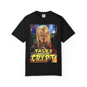 以下が含まれることがあります： 「Tales from the Crypt」のグラフィックが特徴の黒いTシャツ。長い髪の恐ろしい姿と、番組タイトルが黄色とオレンジ色の文字でデザインされています。Tシャツはクルーネックです。
