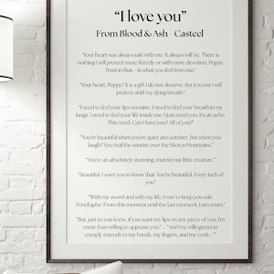 May include: Framed print with the text "I love you" from Blood & Ash - Casteel. The text is in black on a white background, framed in a dark brown frame. The print is displayed on a white brick wall.