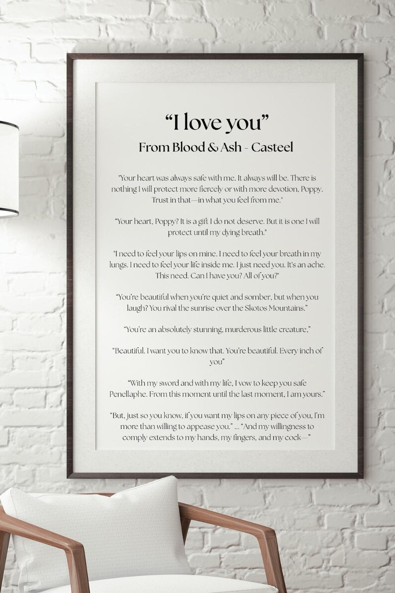May include: Framed print with the text "I love you" from Blood & Ash - Casteel. The text is in black on a white background, framed in a dark brown frame. The print is displayed on a white brick wall.