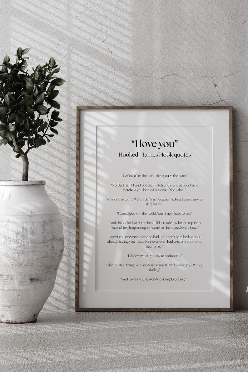 Puede incluir: Una impresi&oacute;n enmarcada con la cita "I love you" y citas de James Hook. La impresi&oacute;n tiene un fondo blanco con texto negro y est&aacute; en un marco de madera. A la izquierda hay una planta decorativa en un jarr&oacute;n blanco.