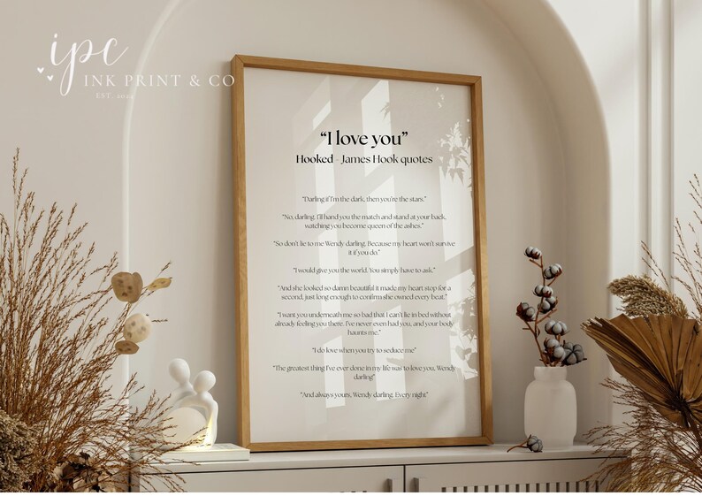 Puede incluir: Una impresi&oacute;n enmarcada con el texto "I love you" y citas de James Hook. La impresi&oacute;n est&aacute; en un marco de madera clara y se exhibe en un estante blanco con elementos decorativos, incluyendo plantas secas y una peque&ntilde;a escultura blanca.
