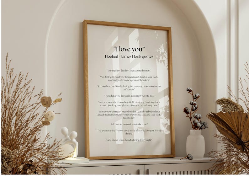 Puede incluir: Una impresi&oacute;n enmarcada con el texto "I love you" y citas de James Hook. La impresi&oacute;n est&aacute; en un marco de madera clara y se exhibe en un estante blanco con elementos decorativos, incluyendo un jarr&oacute;n blanco con una planta y una peque&ntilde;a escultura.