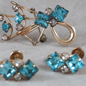 Puede incluir: Un conjunto de pendientes y un broche de tono dorado con diamantes de imitación azules y transparentes. Los pendientes son de estilo clip y el broche tiene un diseño único.