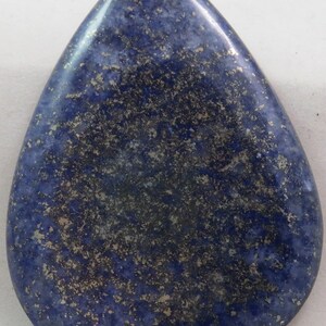 Puede incluir: Un cabujón de lapislázuli en forma de lágrima, de color azul oscuro y con motas de pirita dorada.