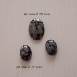 Puede incluir: Tres cabujones ovalados de obsidiana copo de nieve de diferentes tamaños. El más grande mide 25 mm x 18 mm y el más pequeño 18 mm x 12 mm.