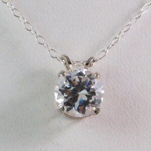 Puede incluir: Un collar de cadena de plata con un gran colgante redondo de circonita cúbica transparente.