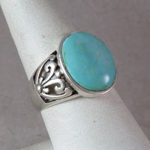 Puede incluir: Un anillo de plata con una piedra turquesa engastada en un diseño de filigrana.