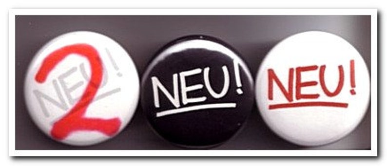 May include: Three round white buttons with black and red text. The first button says "NEU! 2" in red and black. The second button says "NEU!" in white. The third button says "NEU!" in red.