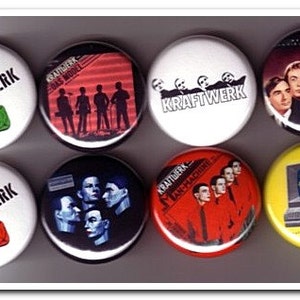 May include: Seven round Kraftwerk band buttons. The buttons feature different album covers and band logos. The buttons are white, red, yellow, and black.
