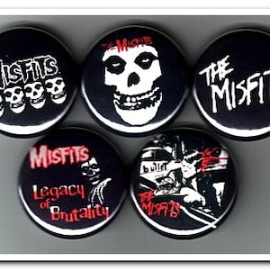 May include: Five black and white Misfits band buttons. The buttons feature the band's name, a skull, and a band logo.
