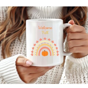 May include: White ceramic mug with a rainbow design and a pumpkin in the center. The text "Welcome Fall" is printed on the mug.
