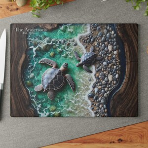May include: A rectangular cutting board featuring a resin art design of two sea turtles swimming in turquoise water near a pebble beach. The board has dark wood grain edges and the text The Andersons Est. 2024 printed in the upper left corner.