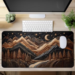 Puede incluir: Alfombrilla de ratón rectangular con un diseño de paisaje montañoso bajo un cielo nocturno. El diseño incluye una luna creciente, estrellas y pinos en tonos marrón, gris y negro. Un ratón y un teclado blancos están sobre el escritorio.