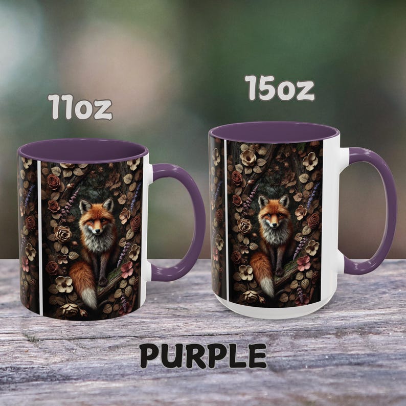 Op de afbeelding: Twee keramische mokken in paars en wit met een vos-illustratie. De mokken zijn verkrijgbaar in de maten 11 oz en 15 oz. De vos is omringd door bloemen en bladeren in een bosrijke omgeving.
