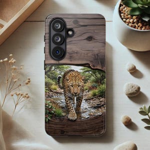 May include: A rectangular smartphone case featuring a wood grain texture on the upper portion and a printed image of a leopard walking through a shallow stream in a forest setting on the lower portion, with three circular camera lenses at the top.