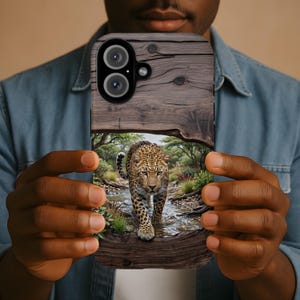 May include: A rectangular smartphone case featuring a printed design of a leopard walking through a shallow stream in a wooded area. The top portion of the case displays a dark brown wood grain pattern, while the lower section shows the leopard.