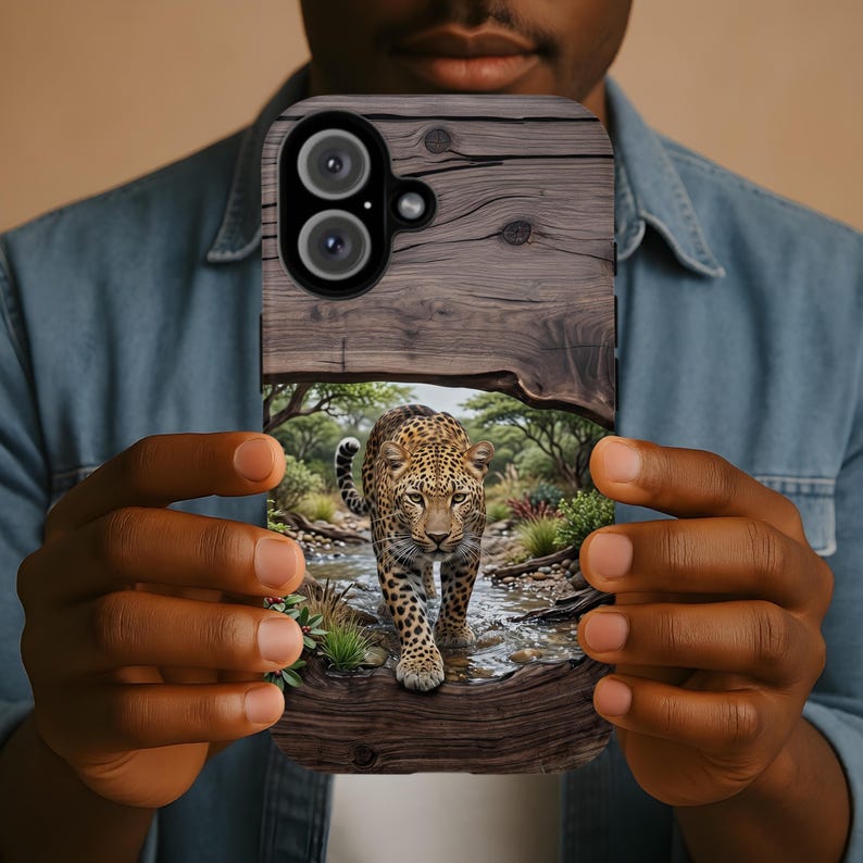 May include: A rectangular smartphone case featuring a printed design of a leopard walking through a shallow stream in a wooded area. The top portion of the case displays a dark brown wood grain pattern, while the lower section shows the leopard.