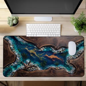 Peut inclure: Un tapis de bureau rectangulaire avec une impression haute résolution représentant une rivière bordée de bois sombre, de l'eau bleue lisse, des galets dispersés et deux dragons de mer feuillus nageant au centre, avec une souris blanche.