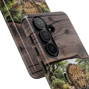 May include: A protective phone case featuring a dark brown wood grain pattern on the upper section and a detailed photographic print of a leopard in a natural savanna environment on the lower section, with cutouts for a triple camera lens system.
