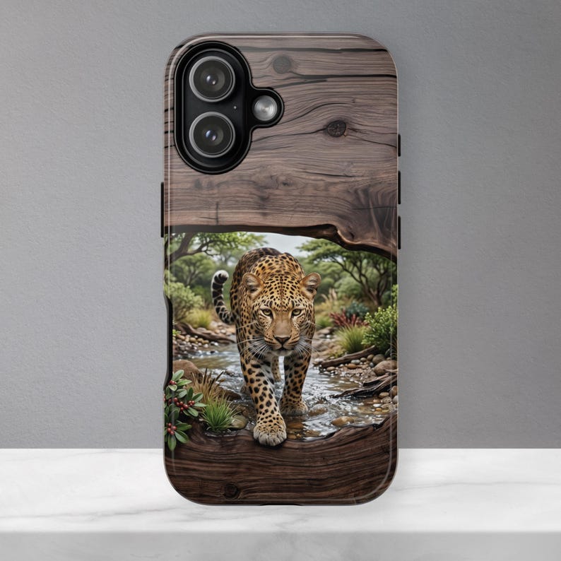 May include: A smartphone case featuring a dark brown wood grain texture on the top and bottom. The center displays a detailed illustration of a leopard walking through a shallow stream in a grassy savanna landscape with green trees and shrubs.
