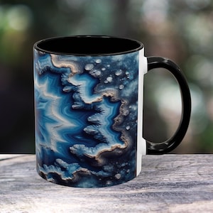 May include: A white ceramic mug with a black rim and handle. The mug features a colorful agate pattern in shades of blue, white, and gold.