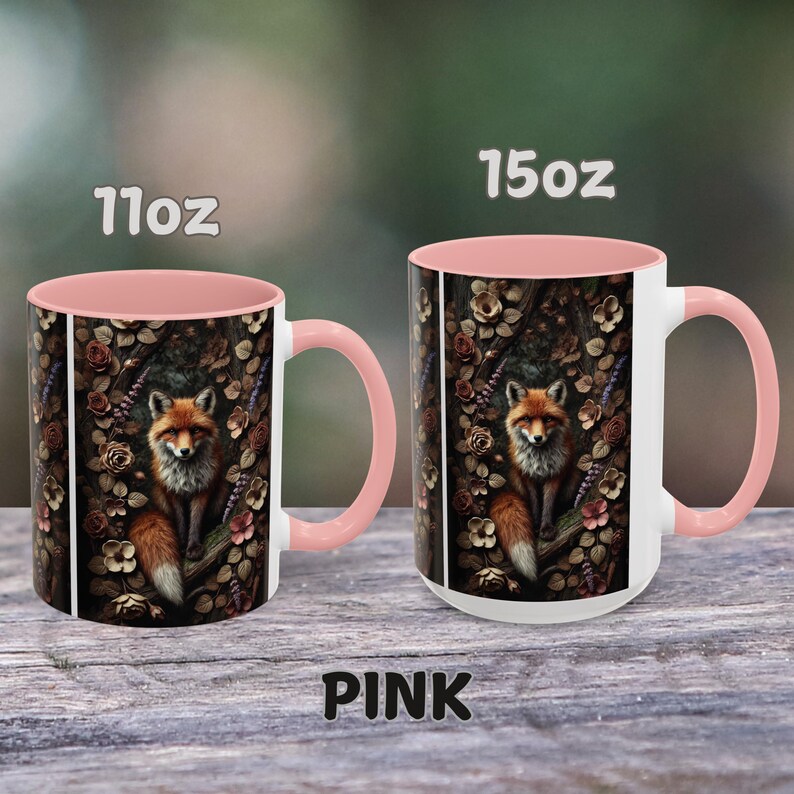 Op de afbeelding: Twee roze en witte keramische mokken met een vos-illustratie. De mokken zijn verkrijgbaar in 11oz en 15oz formaten. De vos is omringd door bloemen en bladeren.