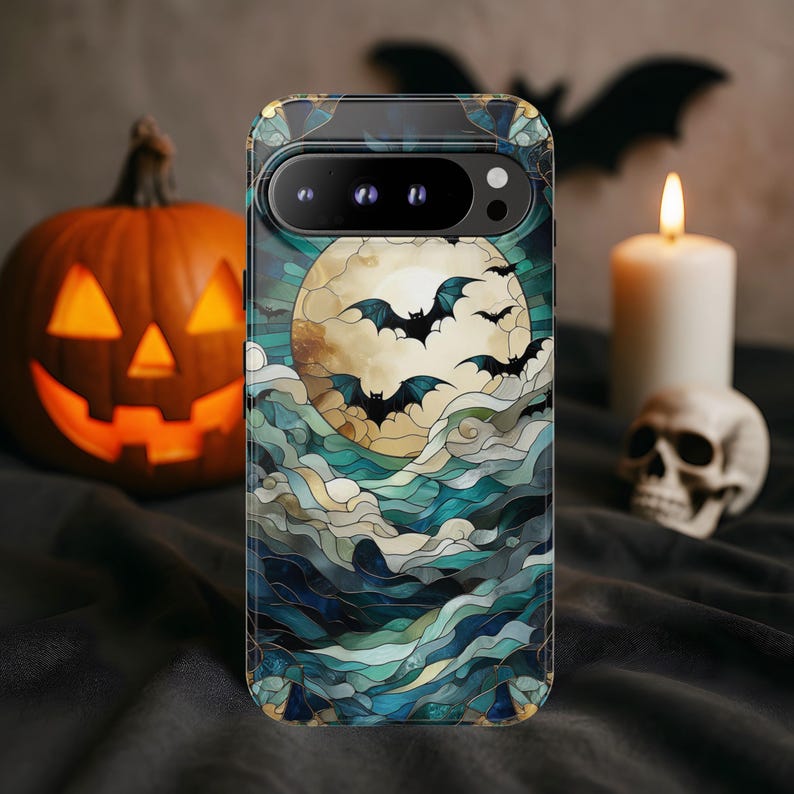 May include: A phone case featuring a Halloween-themed design. The case displays a full moon with bats flying across it, set against a backdrop of stylized clouds in shades of blue and green. The case has a dark border.