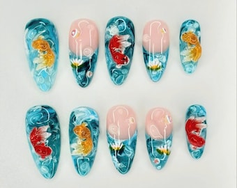 May include: Set of ten false nails with a blue and white water design and red and gold fish painted on them.