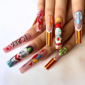 May include: Long, pointed, fake nails with different designs. One nail has the word "LOSER" written on it. Another nail has a clown face with green hair. Another nail has a clown face with red hair. Another nail has a clown face with red hair and a red and yellow striped design. Another nail has a red and yellow striped design. Another nail has a blue and white striped design with a blue drip.