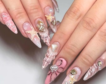 Impresionantes uñas postizas con temática veraniega, juego de uñas almendradas largas con conchas, estrellas de mar y perlas, uñas de verano, uñas playeras y uñas para fiestas.