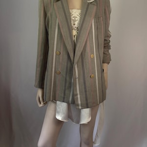 May include: A double-breasted blazer in a muted taupe and brown tone featuring vertical stripes in shades of cream, mauve, and dark brown. The jacket includes notched lapels, long sleeves, and four round gold-toned buttons on the front closure.