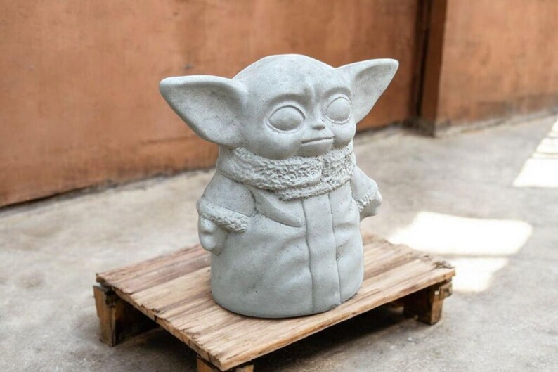 K&ouml;nnte beinhalten: Eine graue Betonstatue einer fiktiven Figur aus dem Star Wars-Franchise. Die Figur tr&auml;gt einen Pelzmantel und hat gro&szlig;e Ohren.