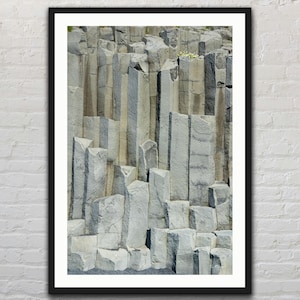 May include: A close-up of a rock formation with tall, vertical columns of gray and black basalt. The columns are arranged in a geometric pattern, creating a striking visual effect.