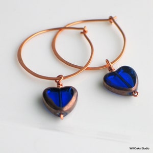 Hand formed & forged copper hoops. Limited edition Czech glass heart beads are wire-wrapped to slide onto the hoop. This charm freely dangles to add movement.