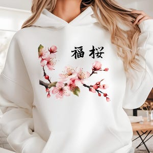 May include: White hoodie with a pink cherry blossom branch and the Chinese characters "福 禄" printed on the front.