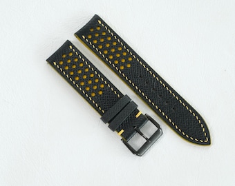 May include: A black watch strap featuring a perforated design with a bright yellow underside visible through the holes. The strap includes yellow contrast stitching along the edges and a black metal buckle, showcasing a textured surface finish.