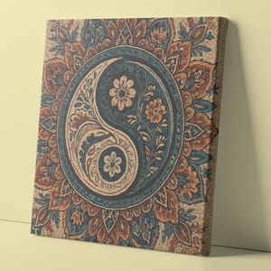 May include: Canvas art print featuring a Yin and Yang symbol in a circular design. The artwork uses a color palette of blue, orange, and beige, with floral and paisley patterns. The canvas is leaning against a light yellow wall.