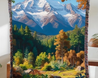 May include: A woven tapestry featuring a scenic landscape with a snow-capped mountain range in the background. The foreground shows a lush forest with green and brown trees, and a grassy area with rocks.