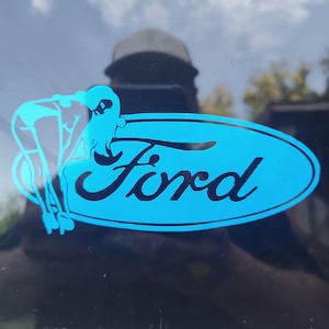 May include: A blue and black Ford logo sticker with a silhouette of a woman in a suggestive pose.