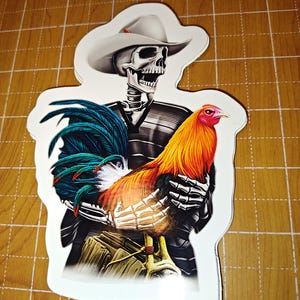 May include: A white skeleton wearing a cowboy hat holds a rooster with orange and red feathers. The rooster is facing the right side of the image. The skeleton is wearing a black and white striped shirt and brown pants.