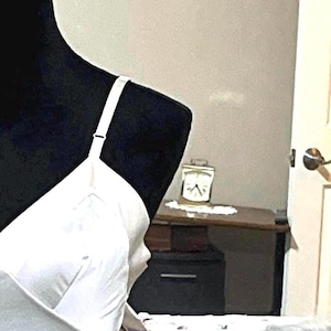 May include: A white satin slip dress with adjustable straps and a scalloped hem. The dress has a V-neckline and is made of a soft, silky fabric.